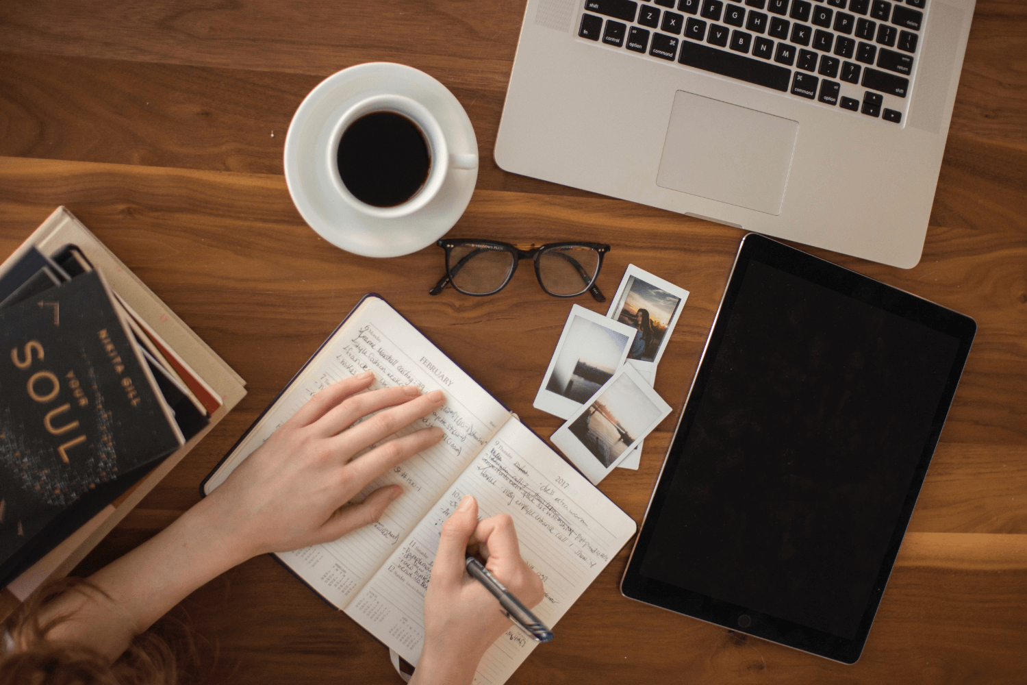 Flat lay of a notebook, laptop, and coffee cup.